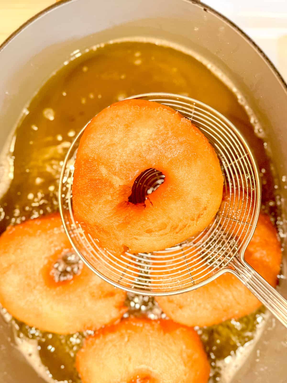 Straining a fried old fashioned buttermilk donut.
