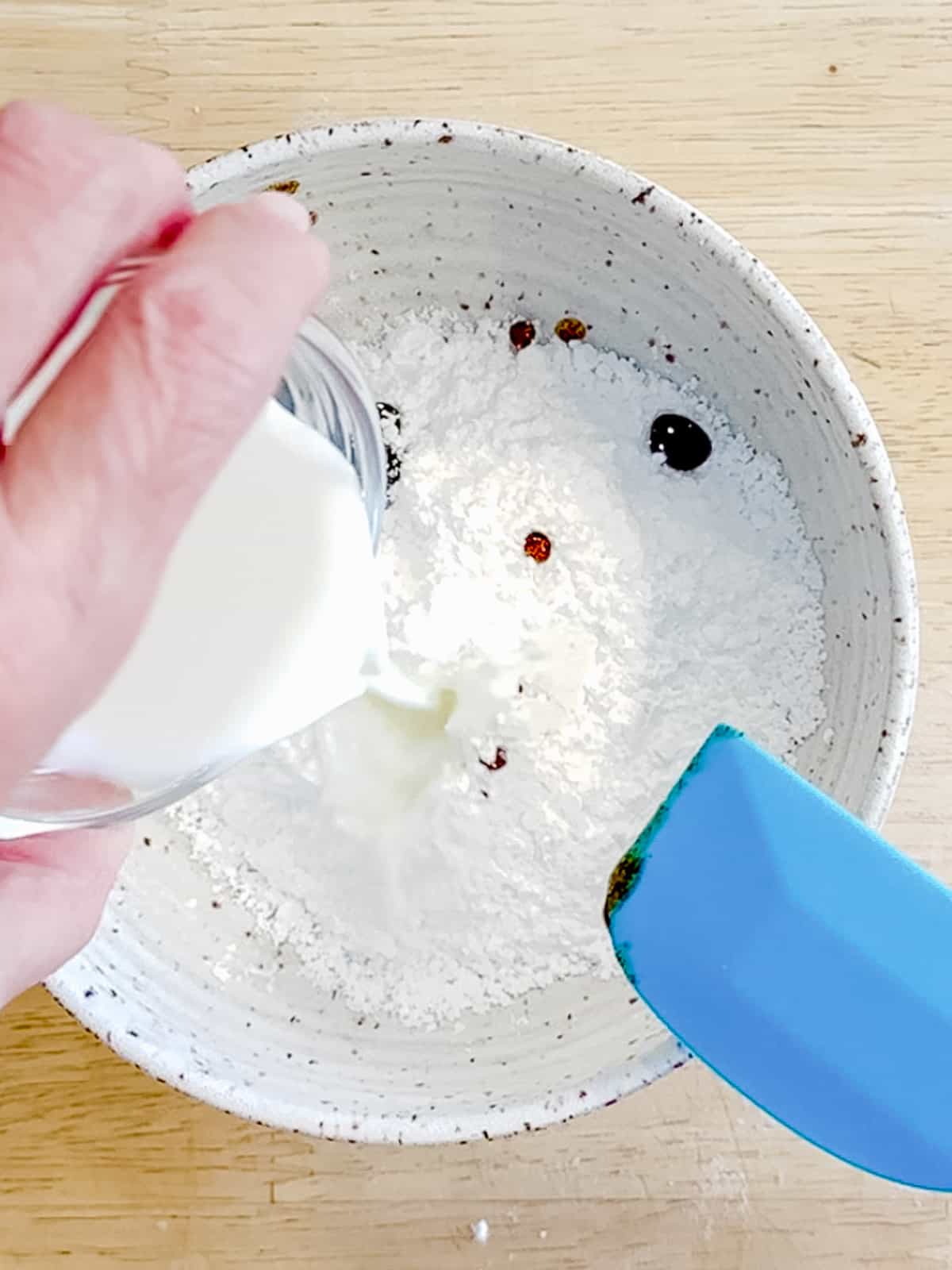 Adding heavy cream to powdered sugar to make glaze.
