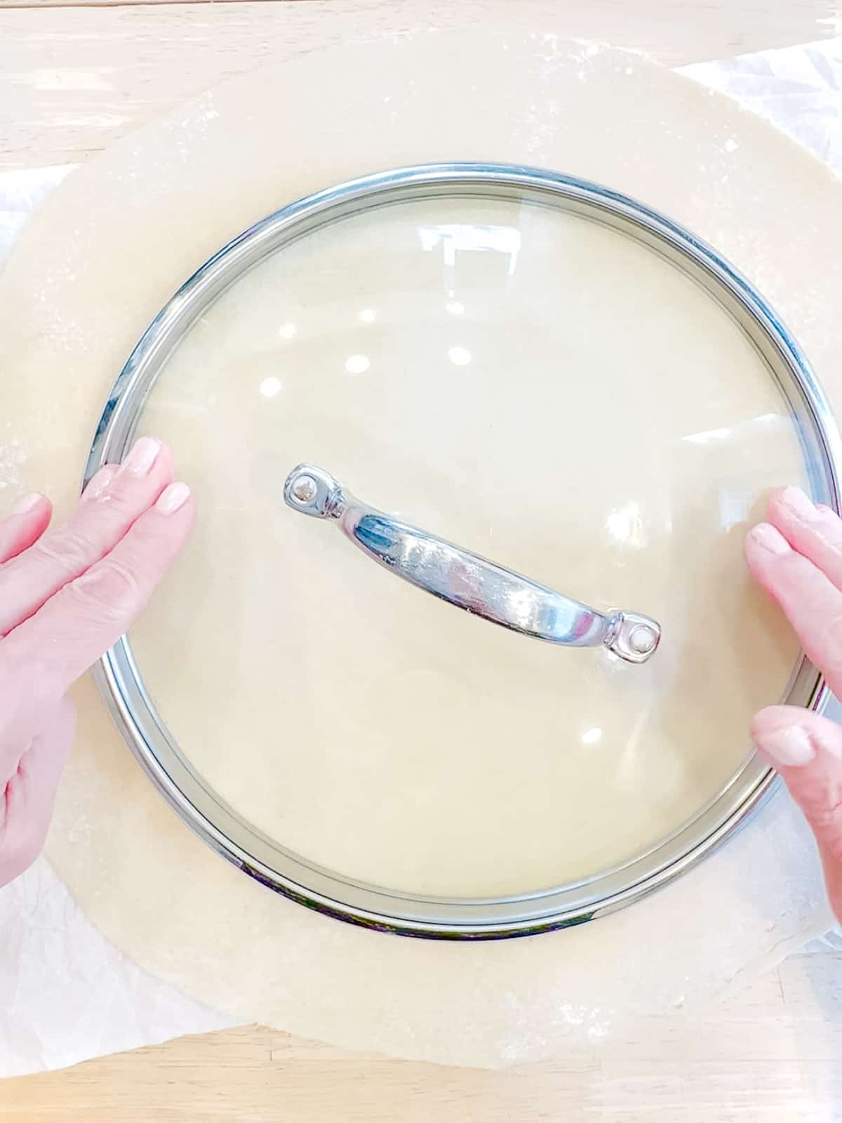 Using a pot lid to mark a circle for a fillings border on galette crust.