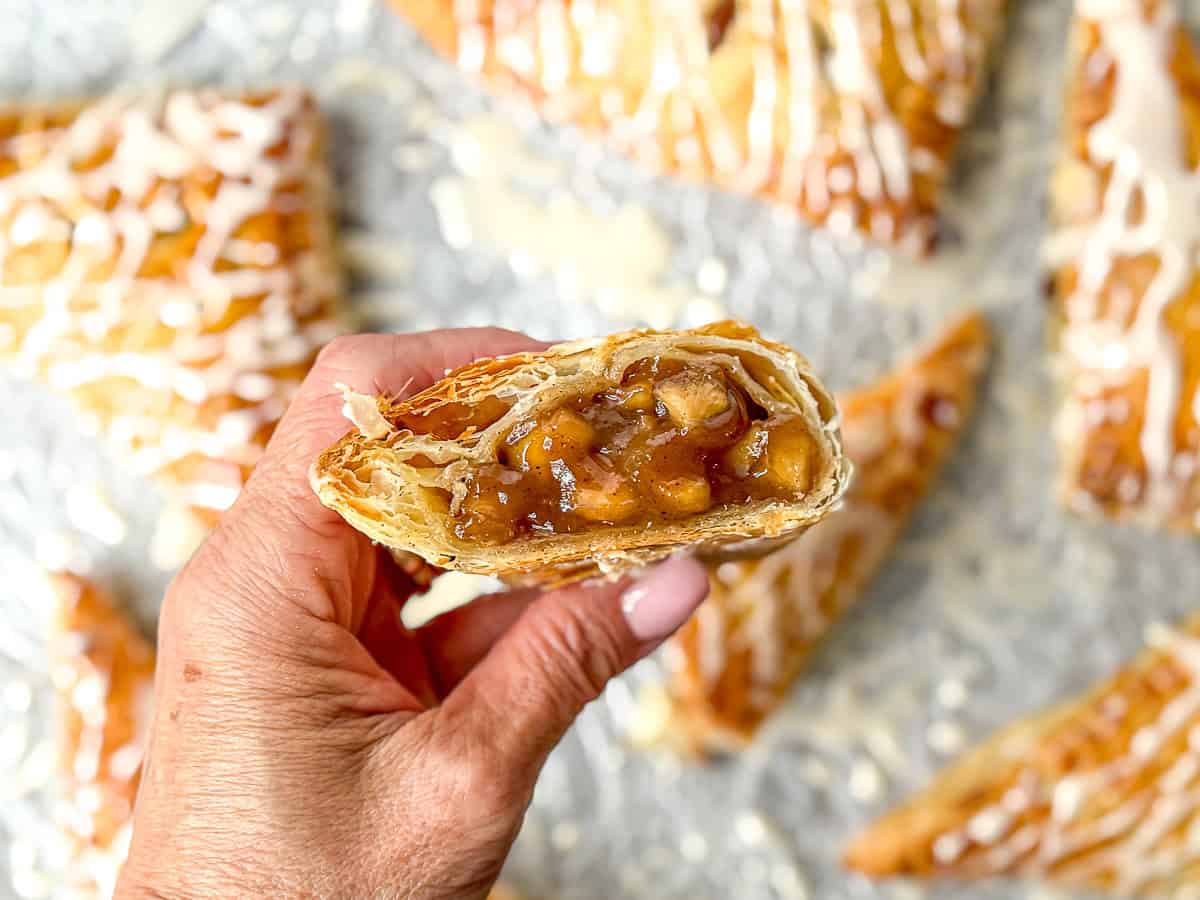 Hand holding a cut open maple apple turnover.