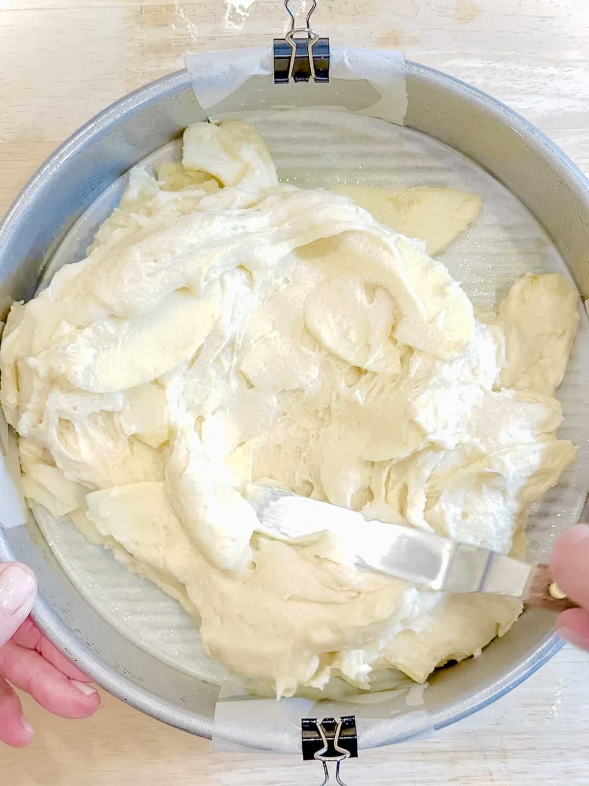Spreading apple cake batter in parchment lined pan.