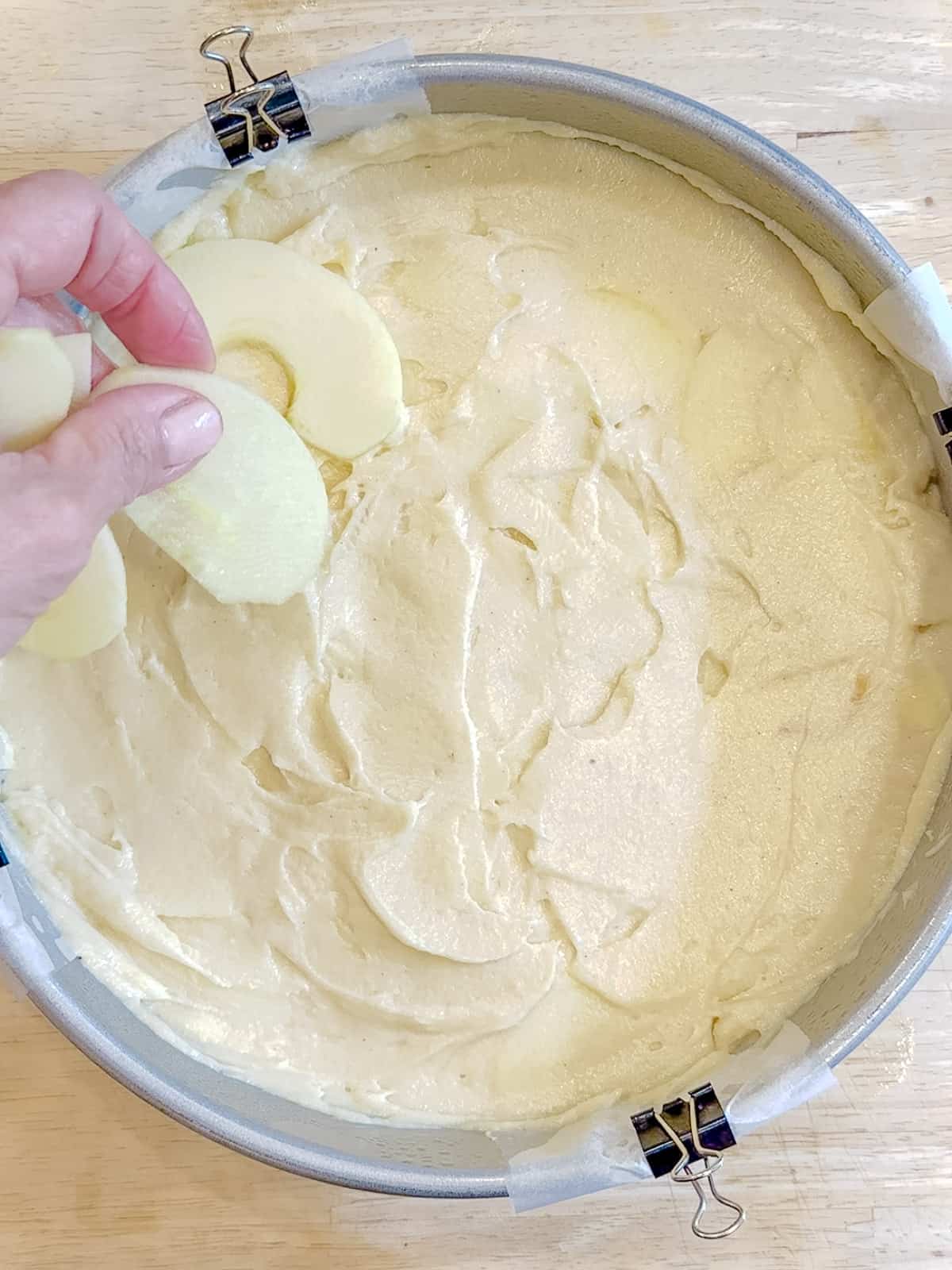 Placing apple slices on top of apple cake before baking.