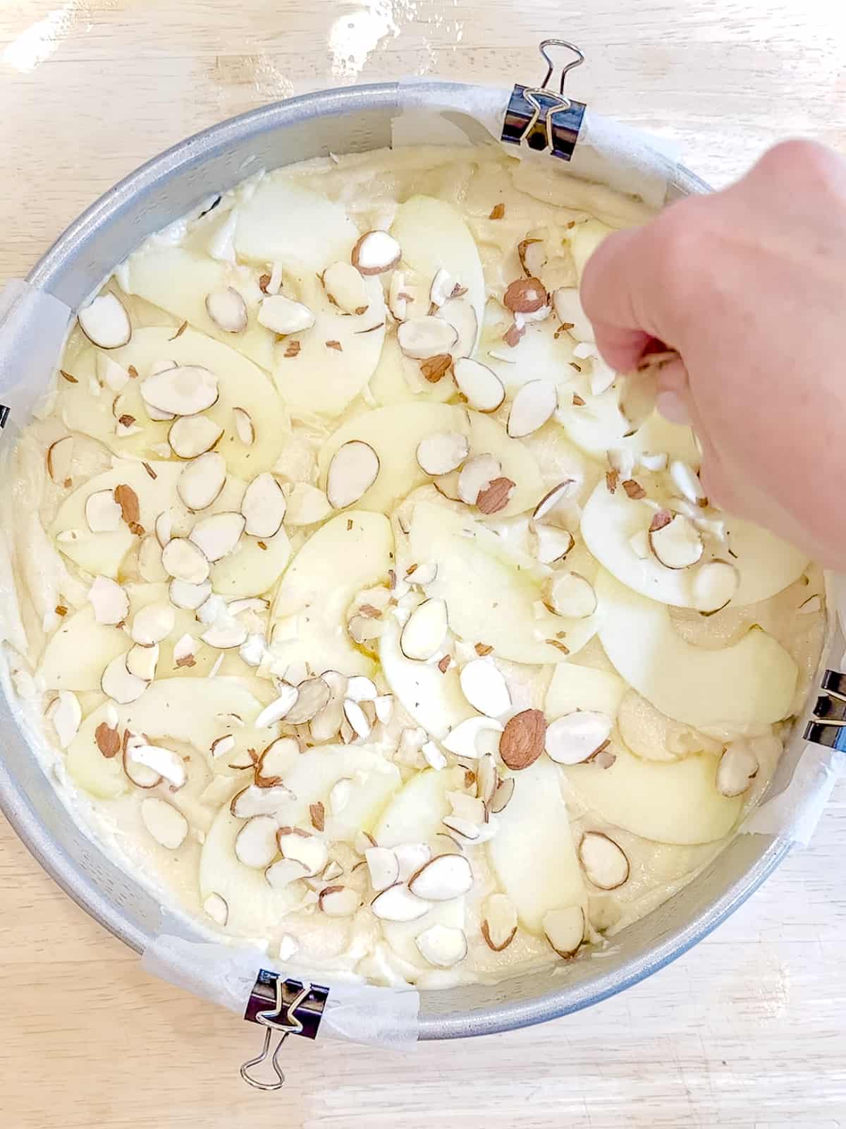 Sprinkling almonds on apple cake before baking.