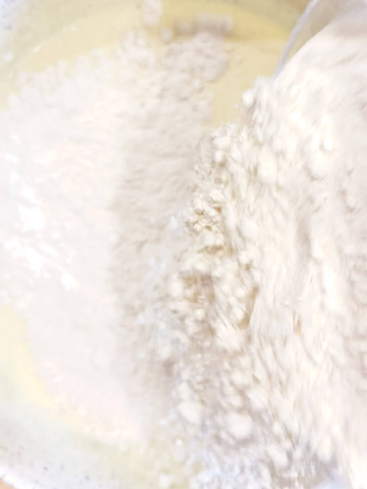 Sprinkling flour over yogurt pancake wet ingredients.