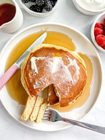Greek yogurt pancakes with fruit, syrup, and yogurt cream.