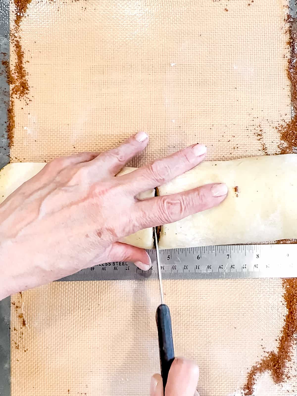 Slicing a log of cinnamon roll dough.