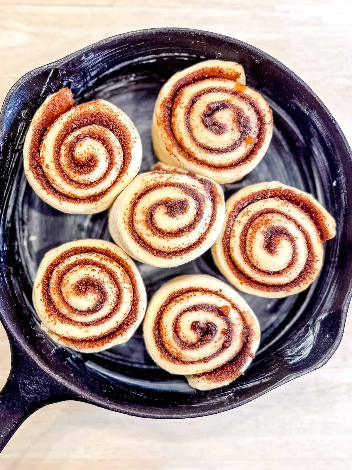 Cut cinnamon rolls in a cast iron pan after rising overnight.