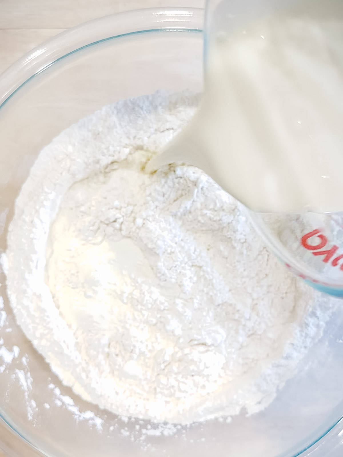 Pouring heavy cream into dry ingredients to make cream biscuits.