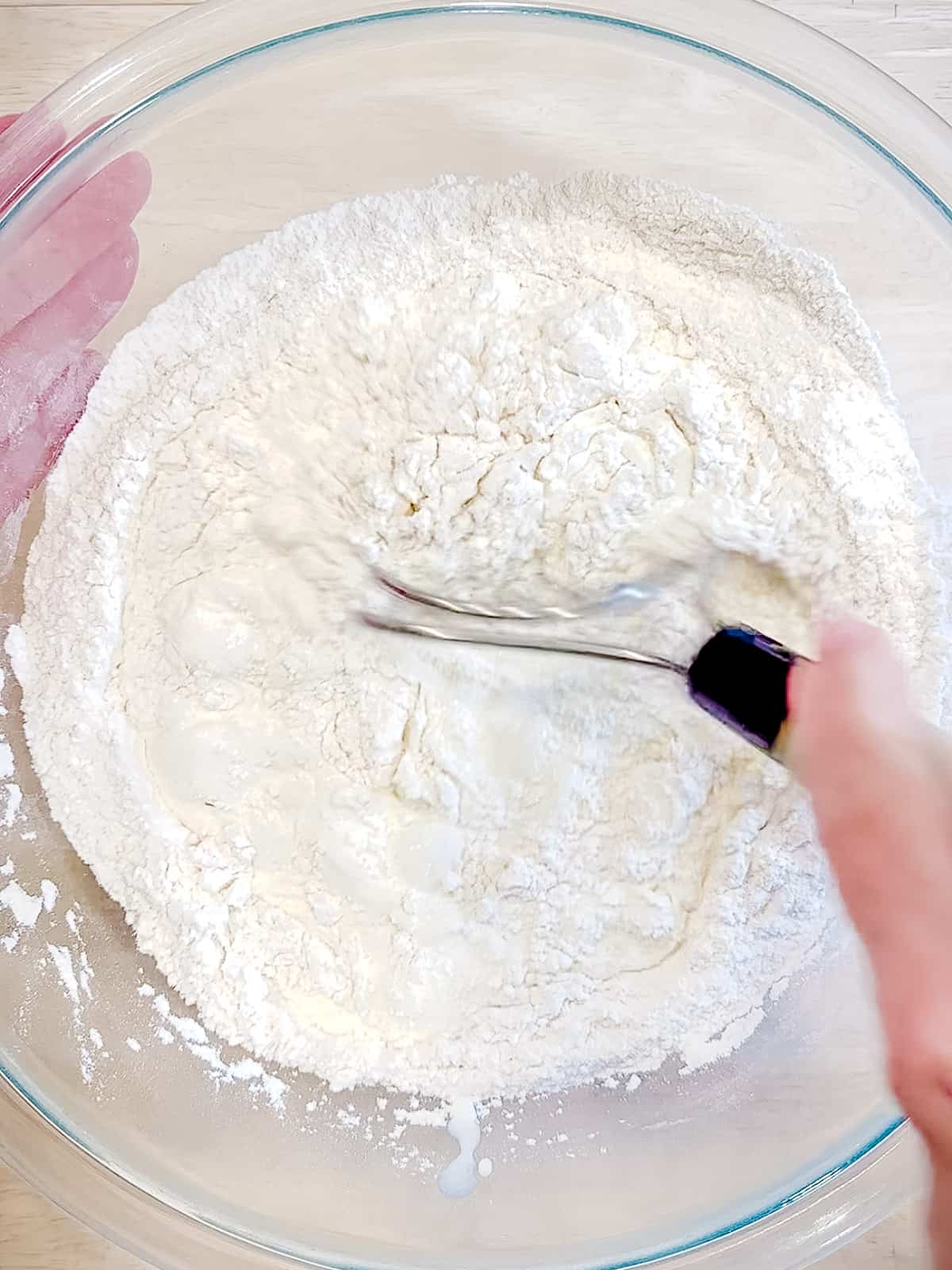 Mixing heavy cream into biscuit ingredients.