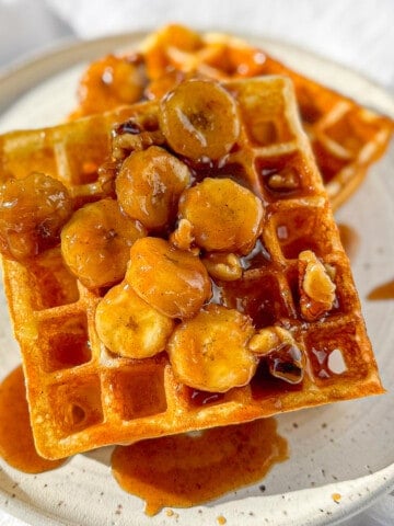 Bananas foster waffles on a white plate.