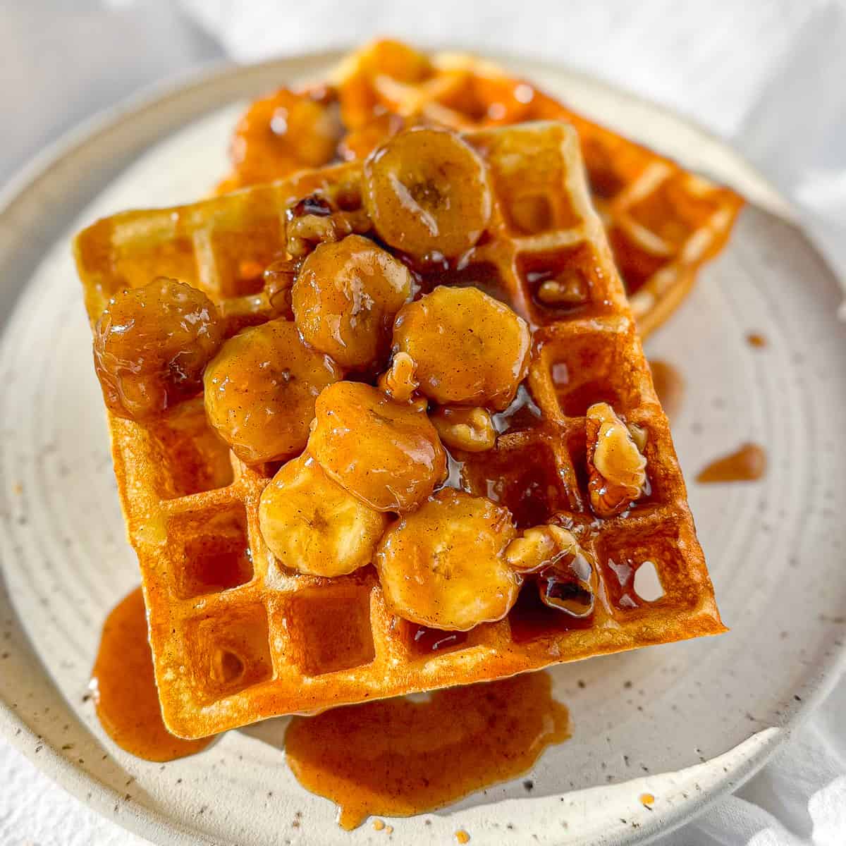Bananas foster waffles on a white plate.