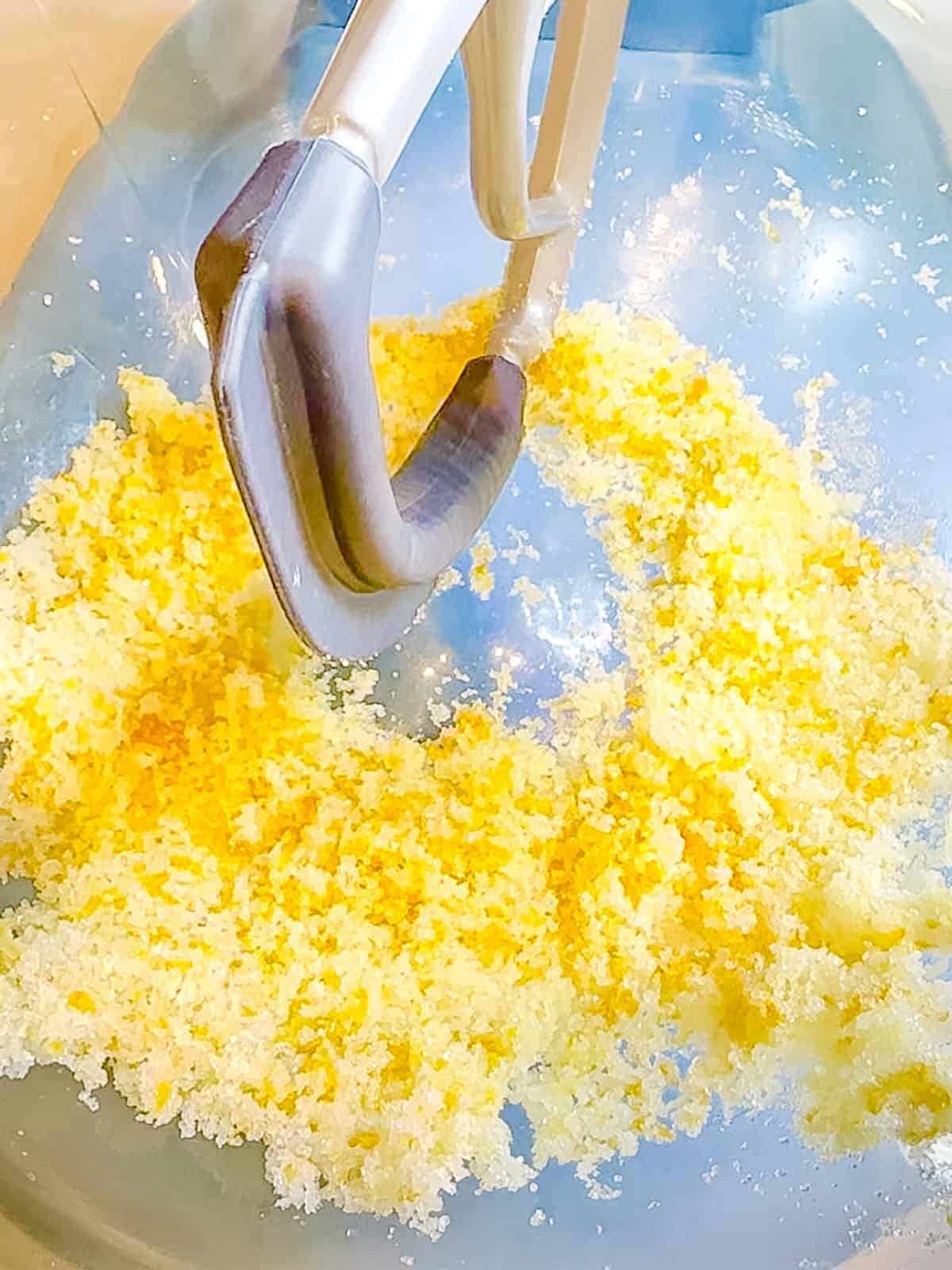 Mixing orange zest with granulated sugar in a stand mixer.