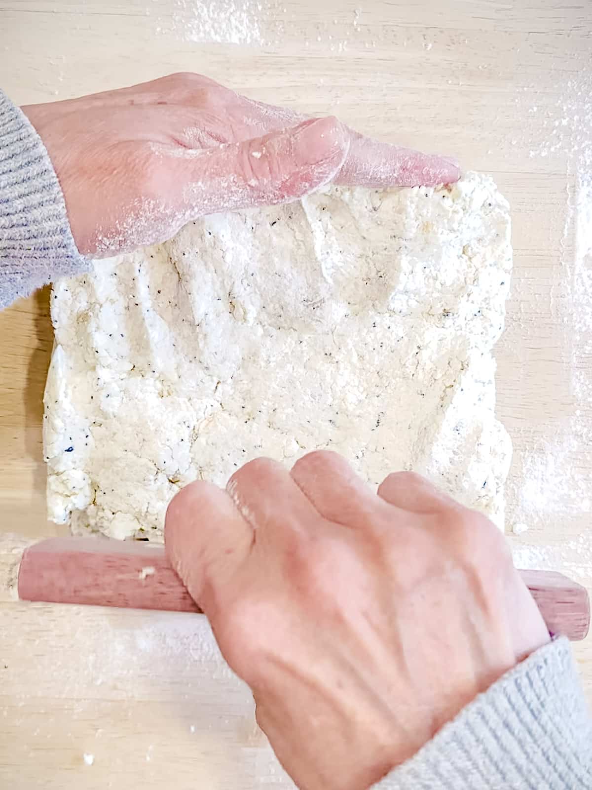Using a bench scraper to shape biscuit dough into a square.