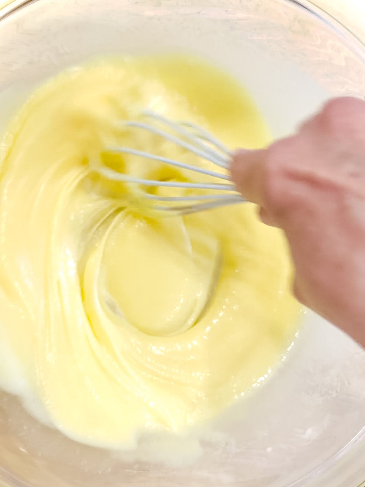 Whisking together eggs, sugar, eggs, and sour cream for muffins.
