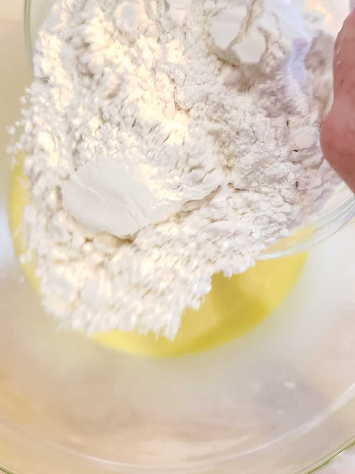 Adding flour to muffin batter wet ingredients.