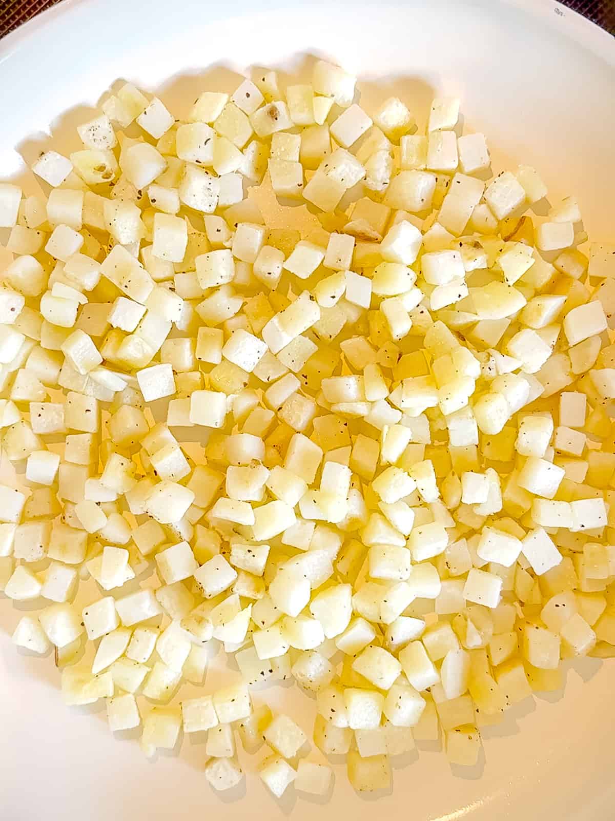 Sautéing diced potatoes in a pan.
