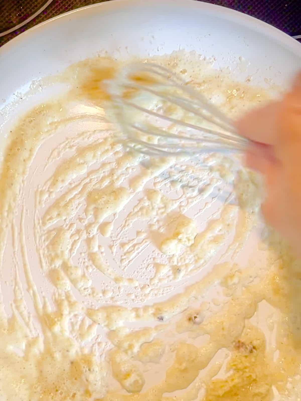 Whisking flour and butter together to make a roux.