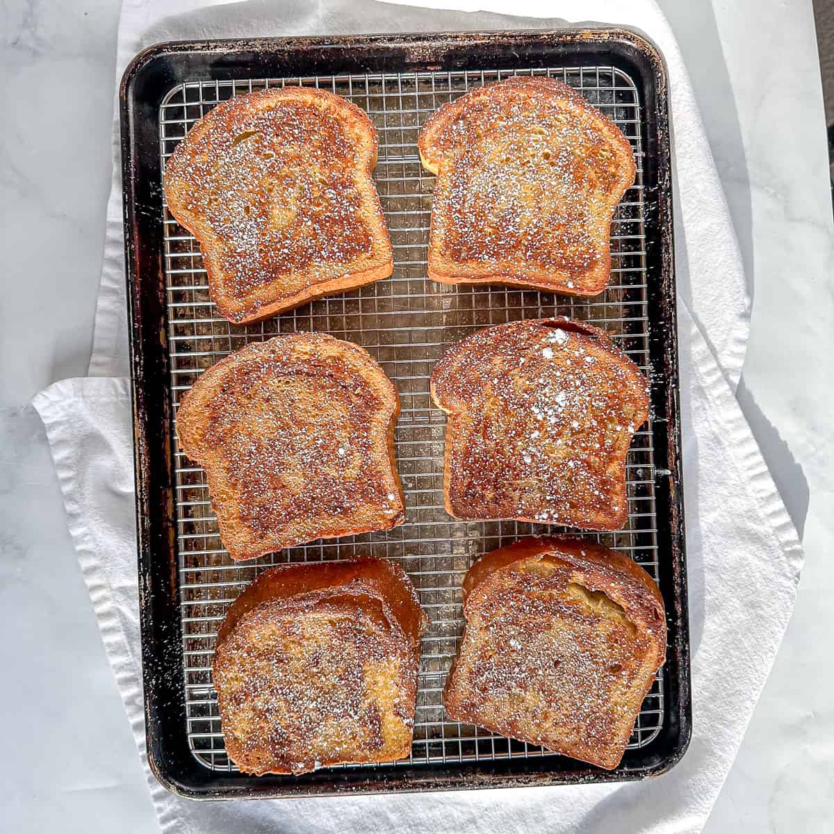 Six slices of French toast sprinkled with cinnamon powdered sugar.
