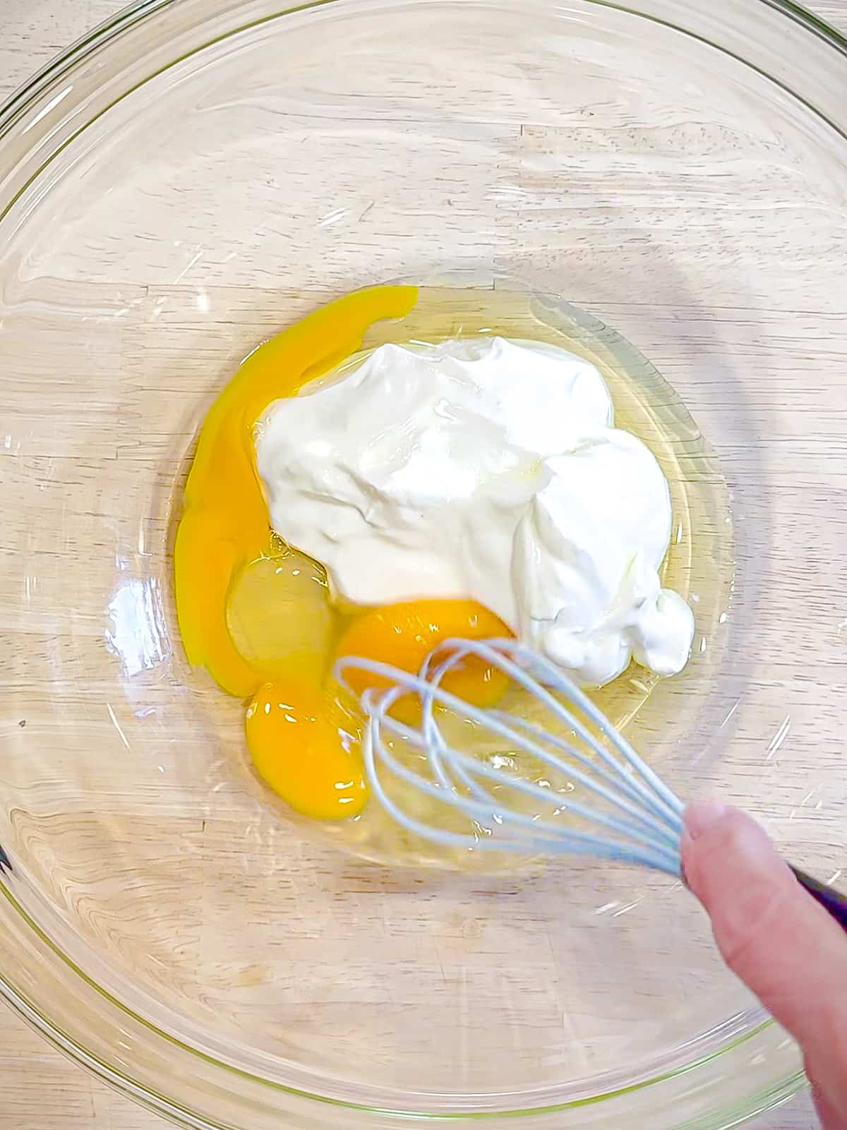 Whisking together Greek yogurt and eggs.