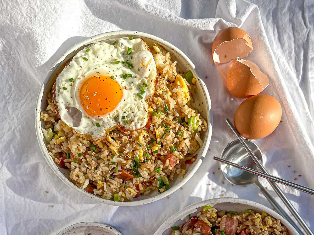 Two bowls of egg fried rice, one with an egg on top.