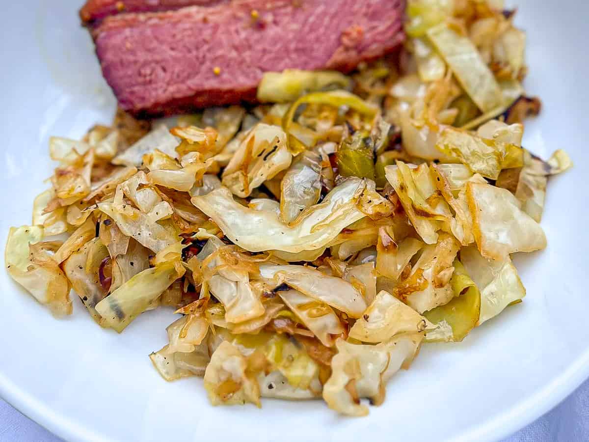 Close up of southern fried cabbage and corn beef on a white plate.