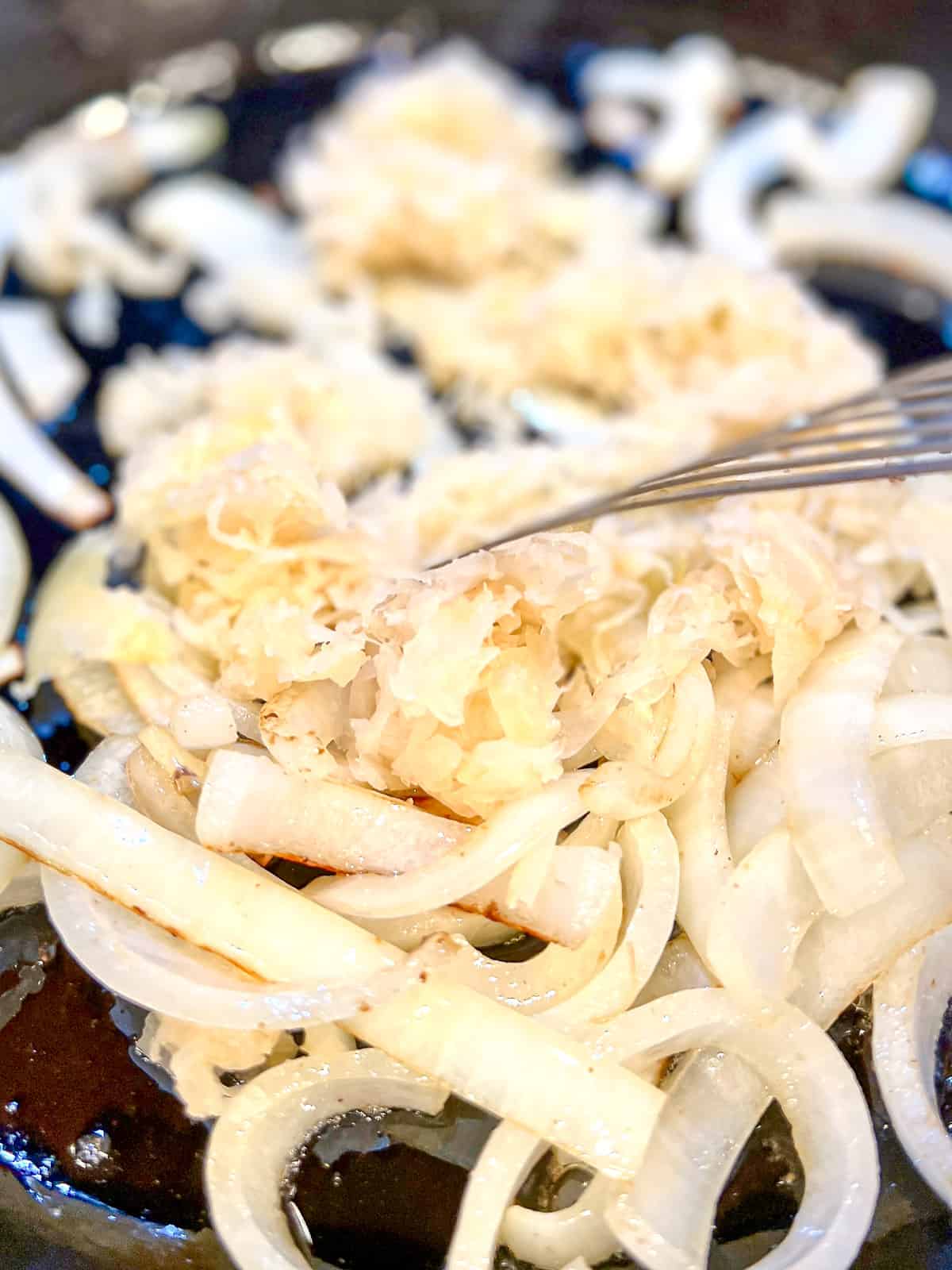 Sautéing onions, and sauerkraut in a cast iron pan.