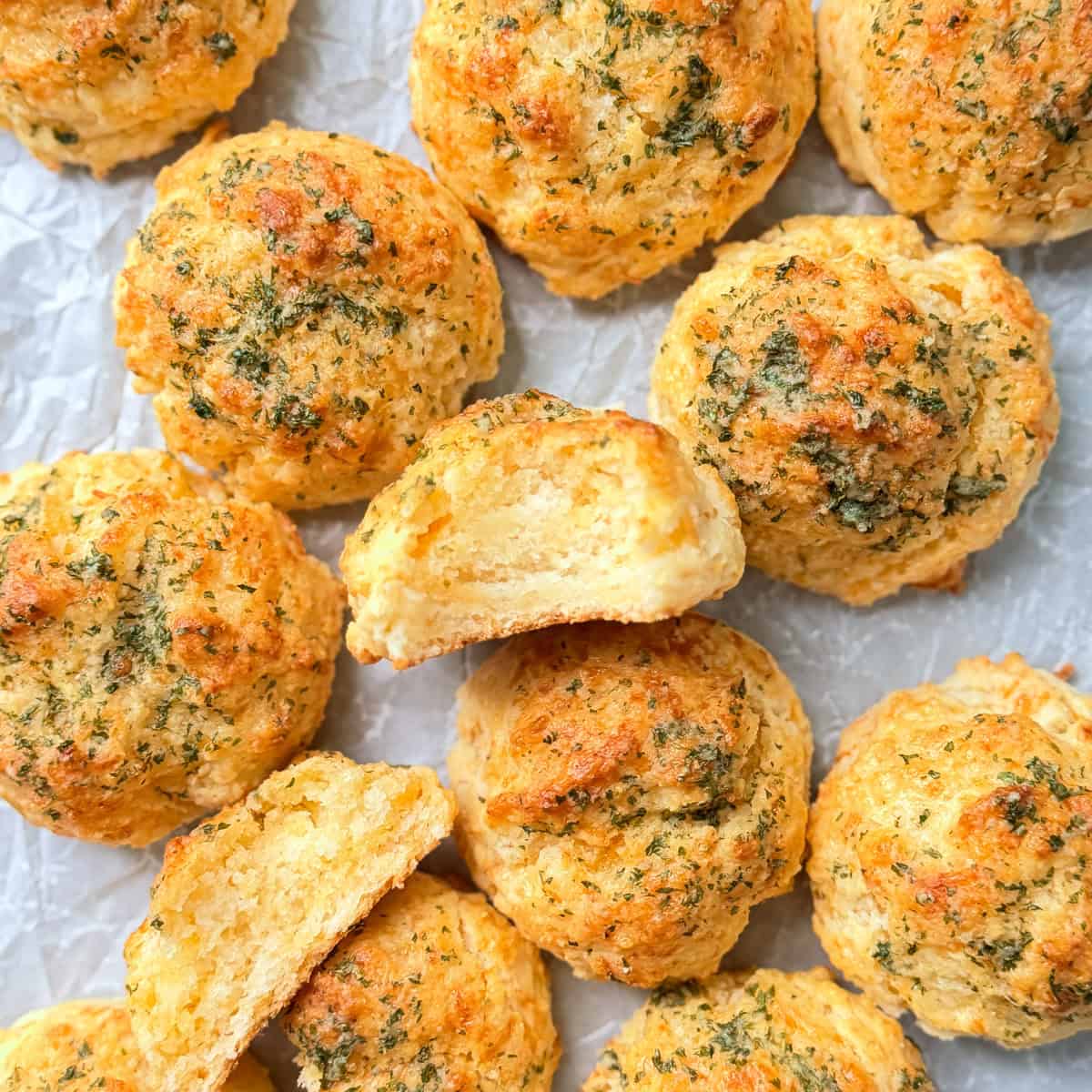 Cheddar Bay biscuits on a parchment paper covered pan.
