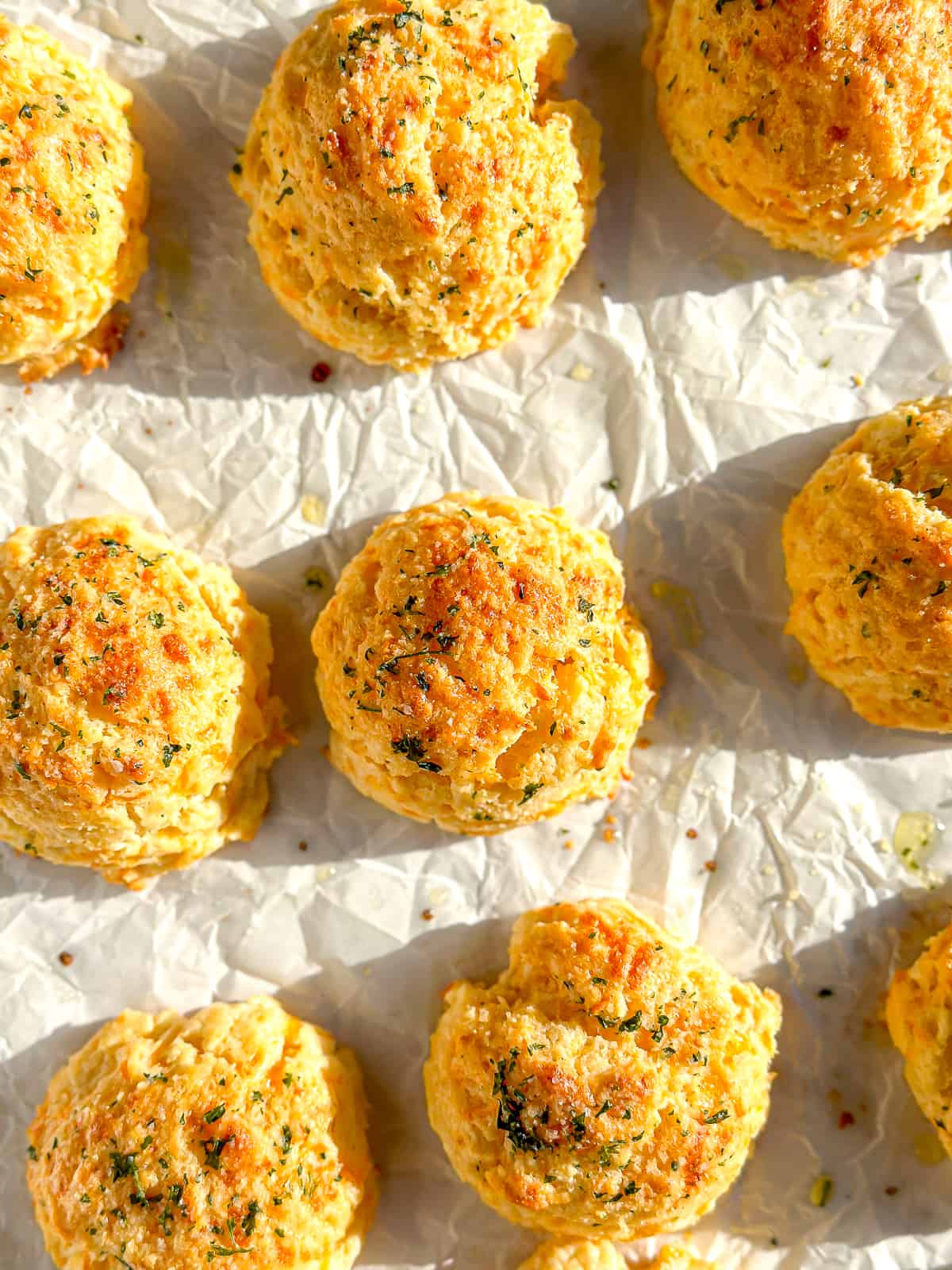 Easy cheddar bay biscuits on a parchment paper lined sheet pan.