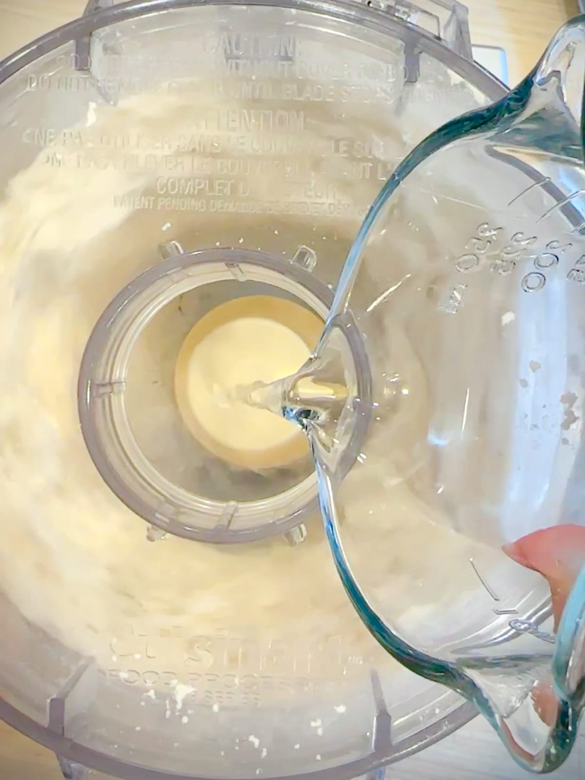 Pouring water into a food processor to make pie dough.