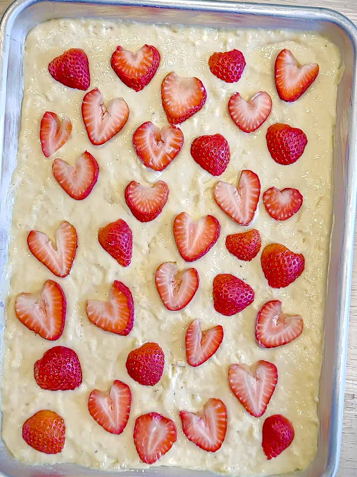 Placing strawberries on top of unbaked strawberry sheet pan pancakes.