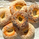 A pile of bagels on parchment paper.