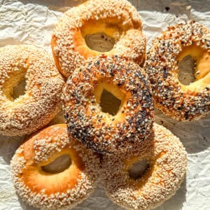 A pile of bagels on parchment paper.