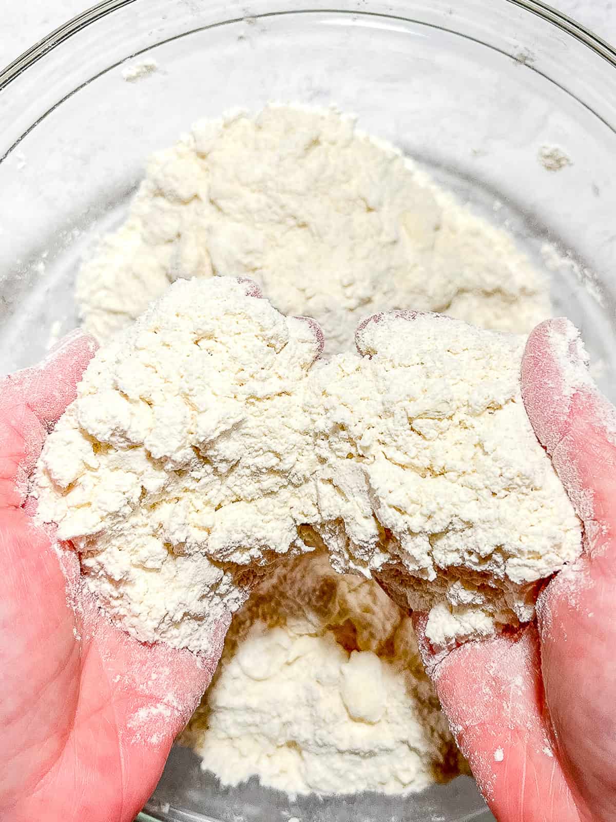 Using hands to check texture of butter and flour mixture for cat head biscuits.