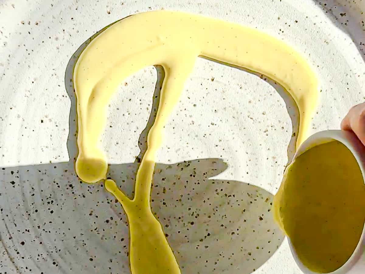 Pouring crème anglaise onto a white plate.