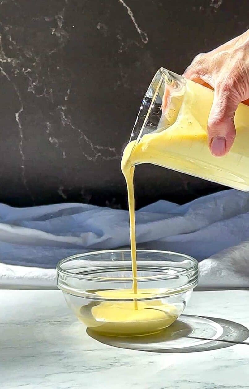 Pouring crème anglaise into a bowl from a measuring cup.