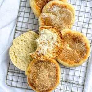 Quick and easy English muffins on a wire rack, one smeared with butter.