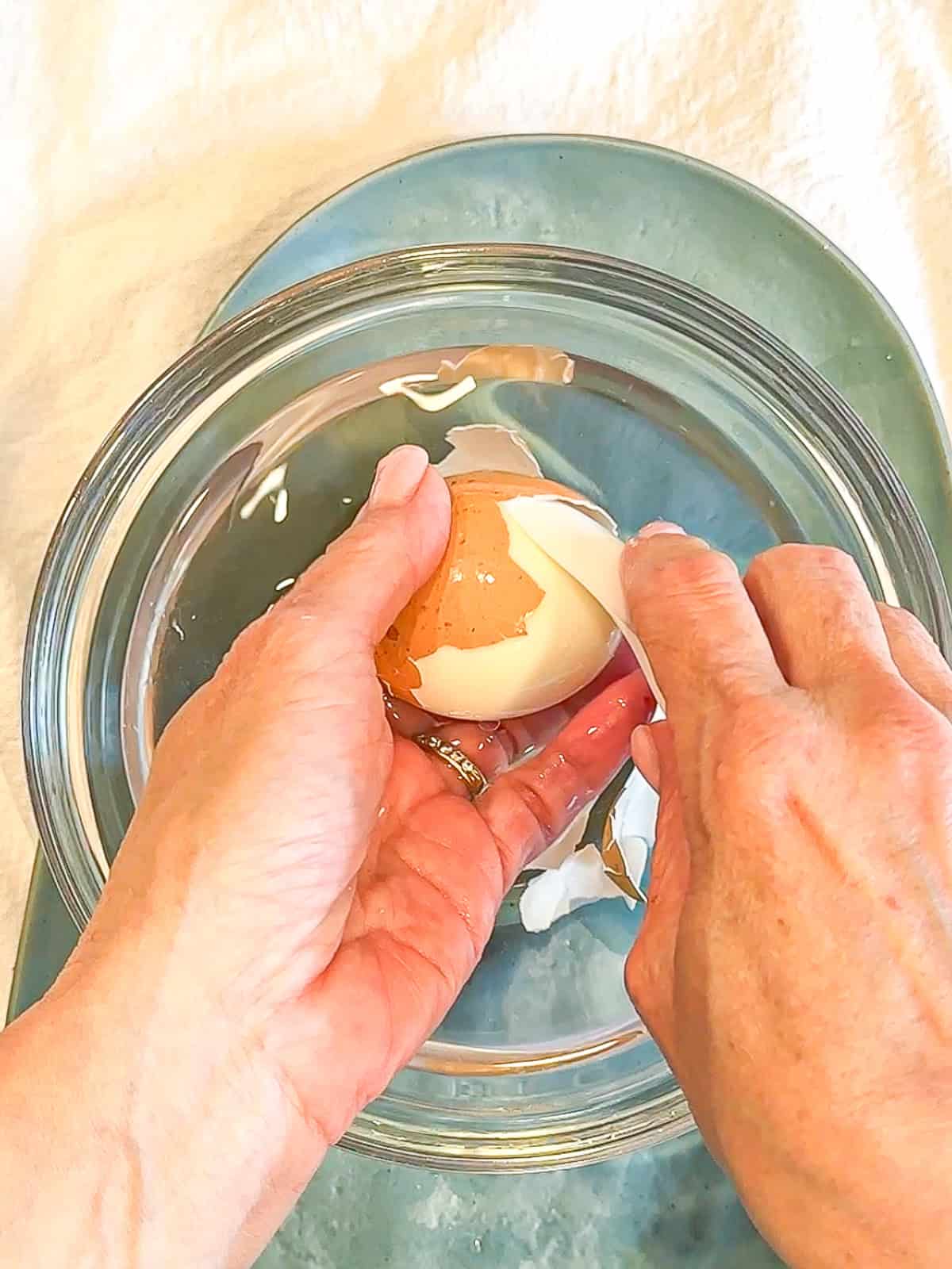 Using a spoon to loosen and remove egg shell from hard boiled egg.
