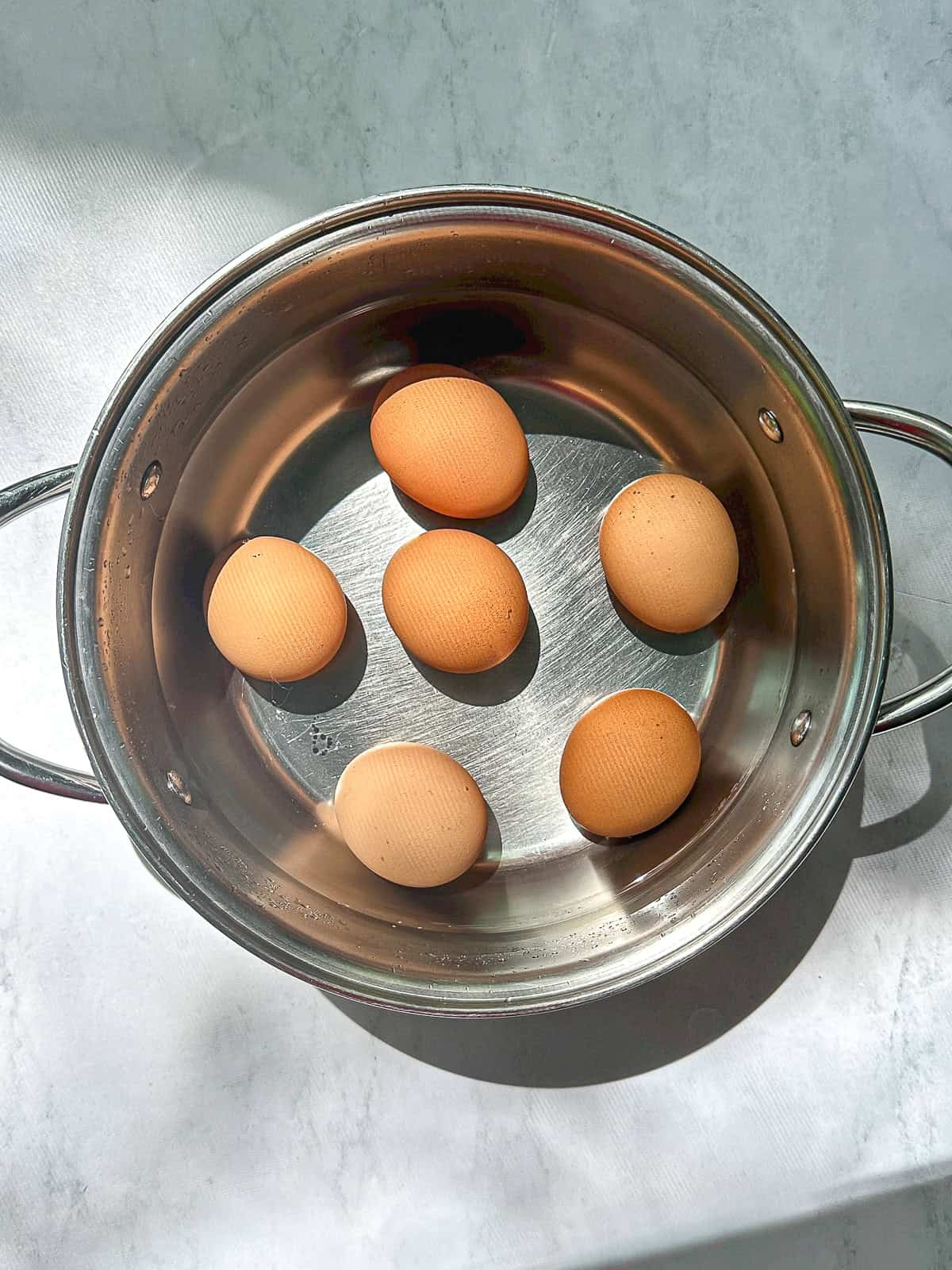 Eggs in a pot of cold water.