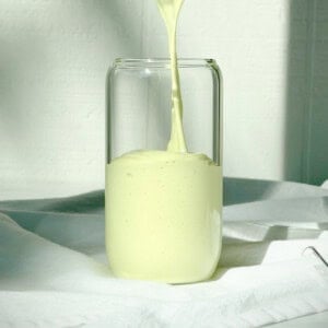 Pouring an avocado banana smoothie into a glass.