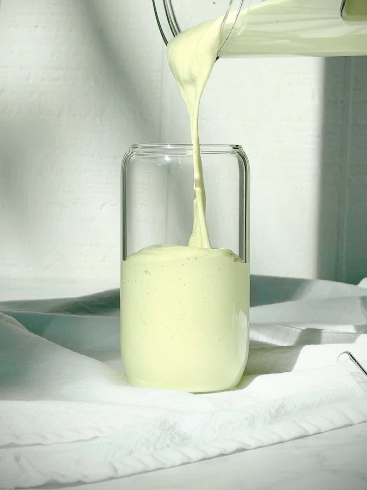 Pouring an avocado banana smoothie into a glass.