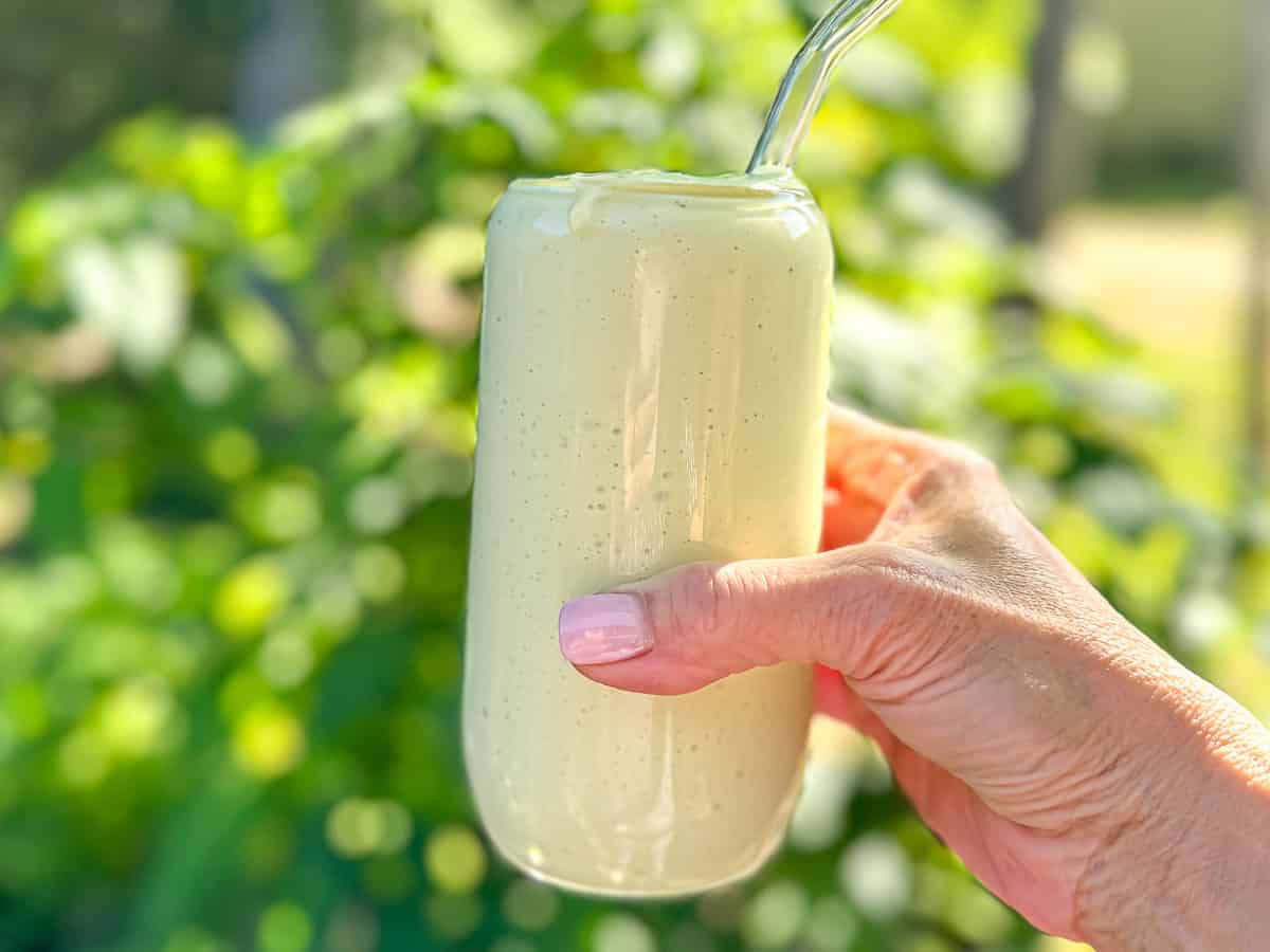 The author's hand holding an avocado banana smoothie.