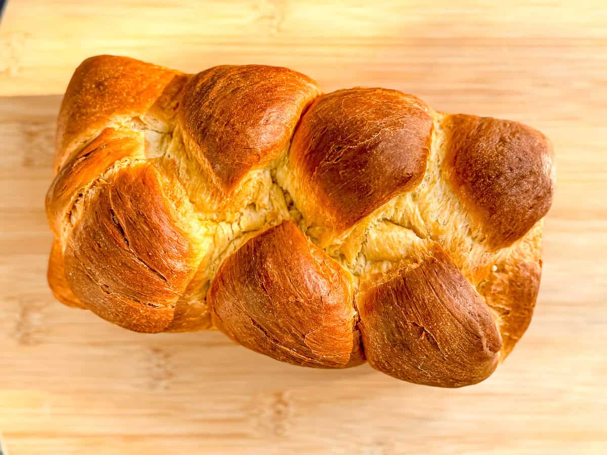 Braided brioche on a wooden cutting board.