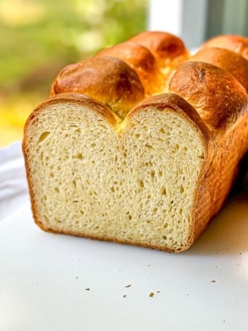 A sliced open brioche bread loaf in a sunny window.