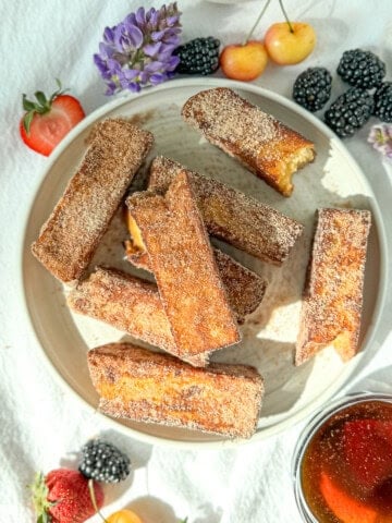Cinnamon sugar french toast sticks on a white plate.