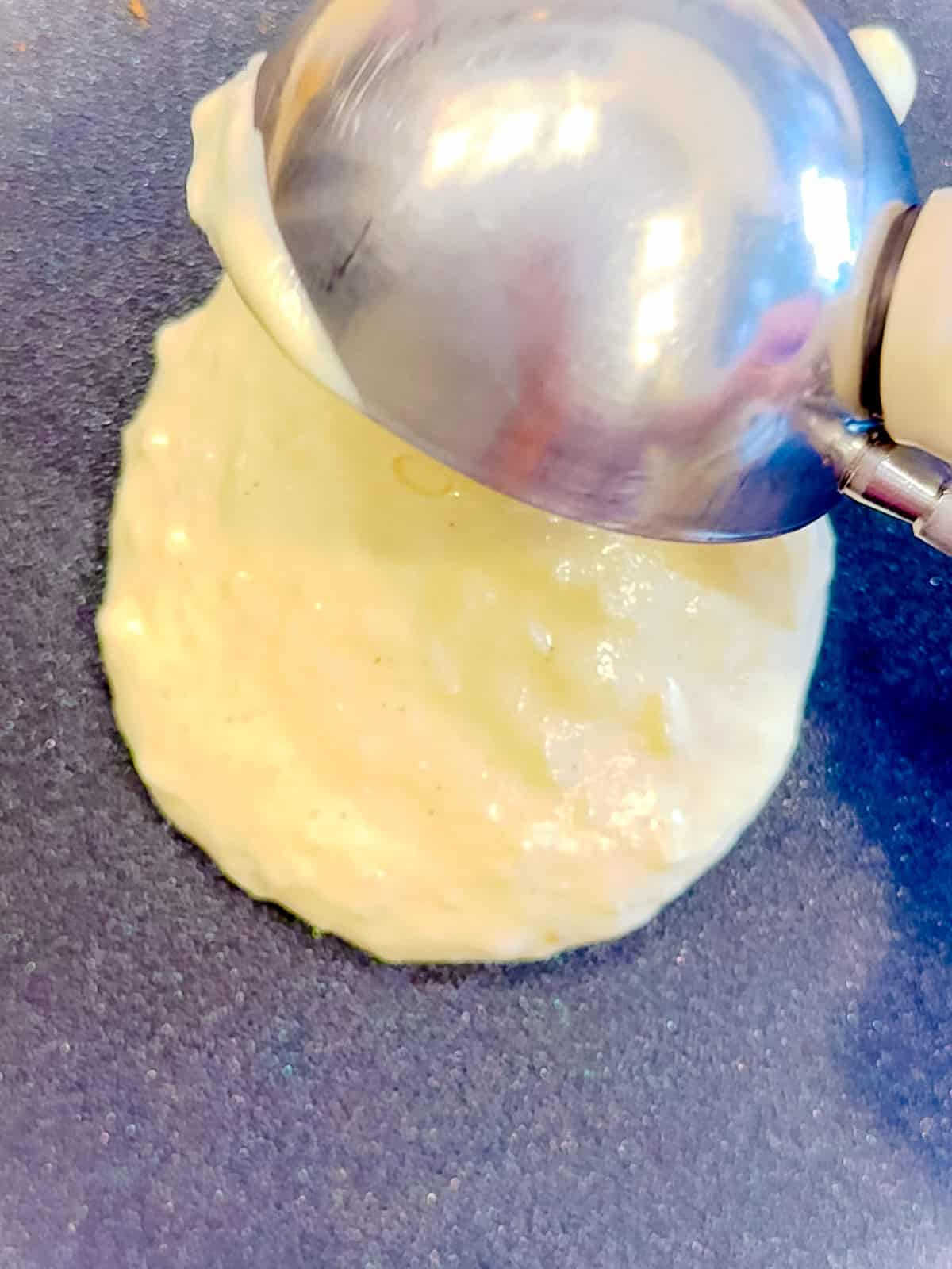 Scooping pancake batter onto nonstick pan.