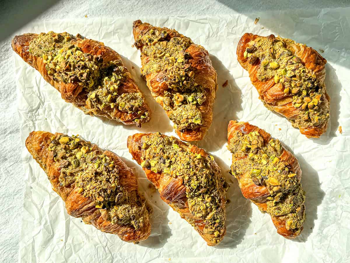 Baked pistachio filled croissants on parchment paper.