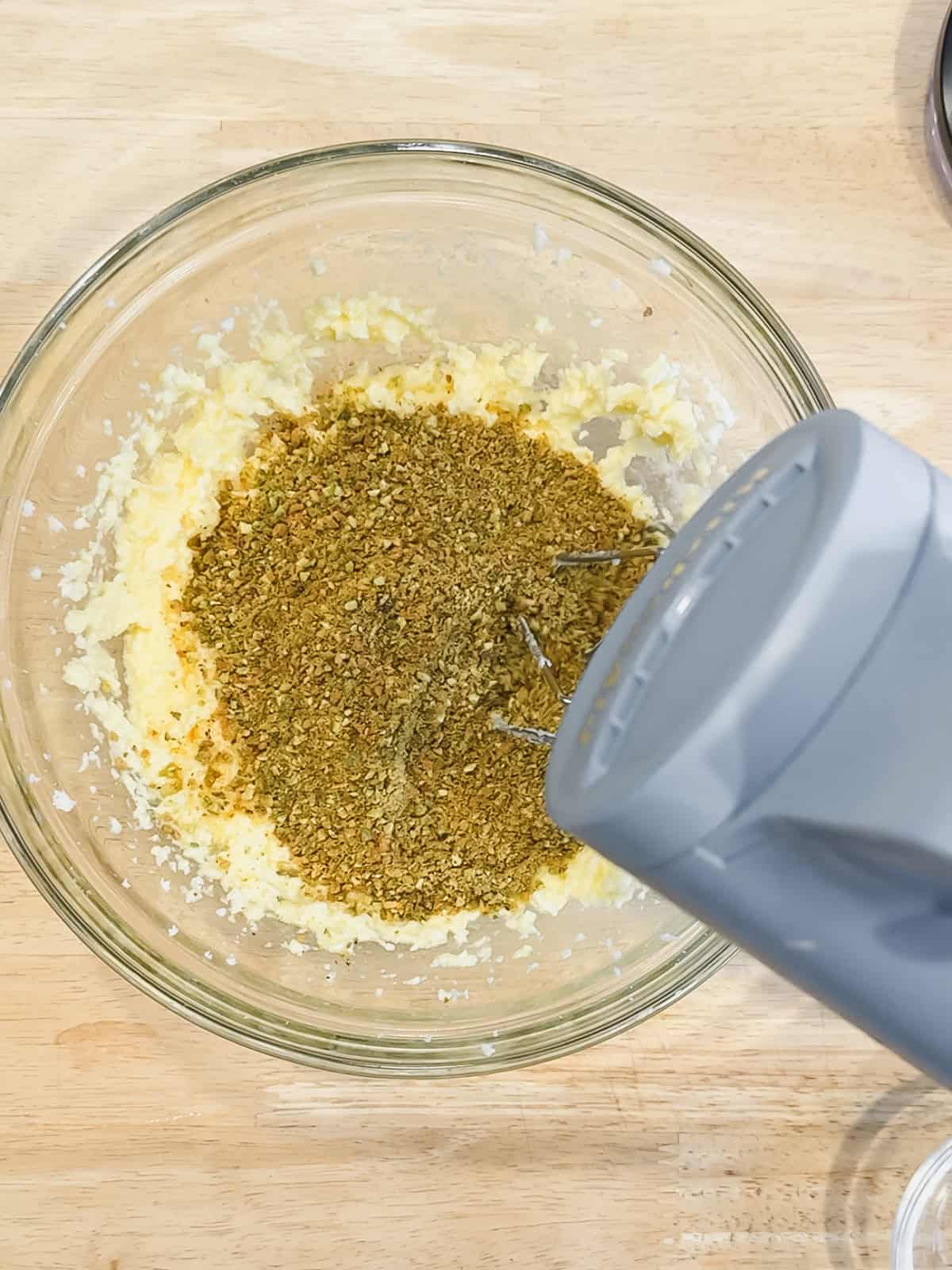 Mixing eggs and pistachio flour into creamed butter and sugar to make pistachio cream.