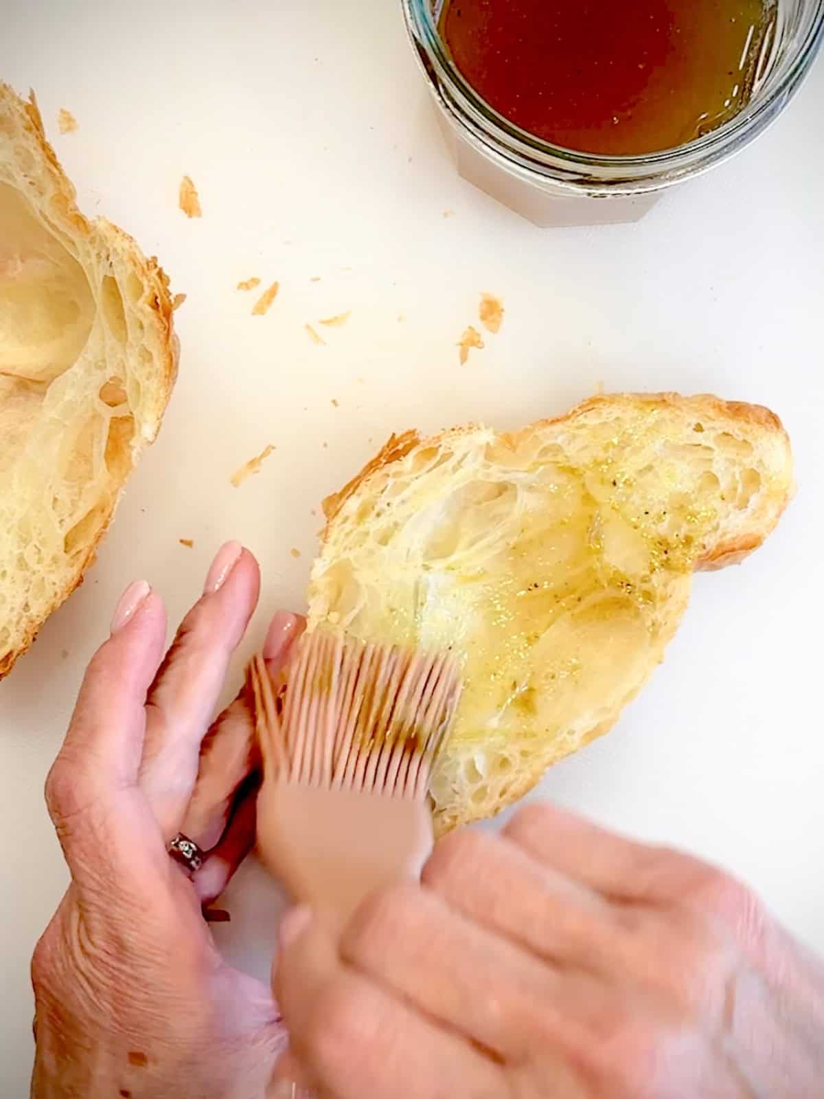 Brushing pistachio syrup on the cut insides of a croissant.