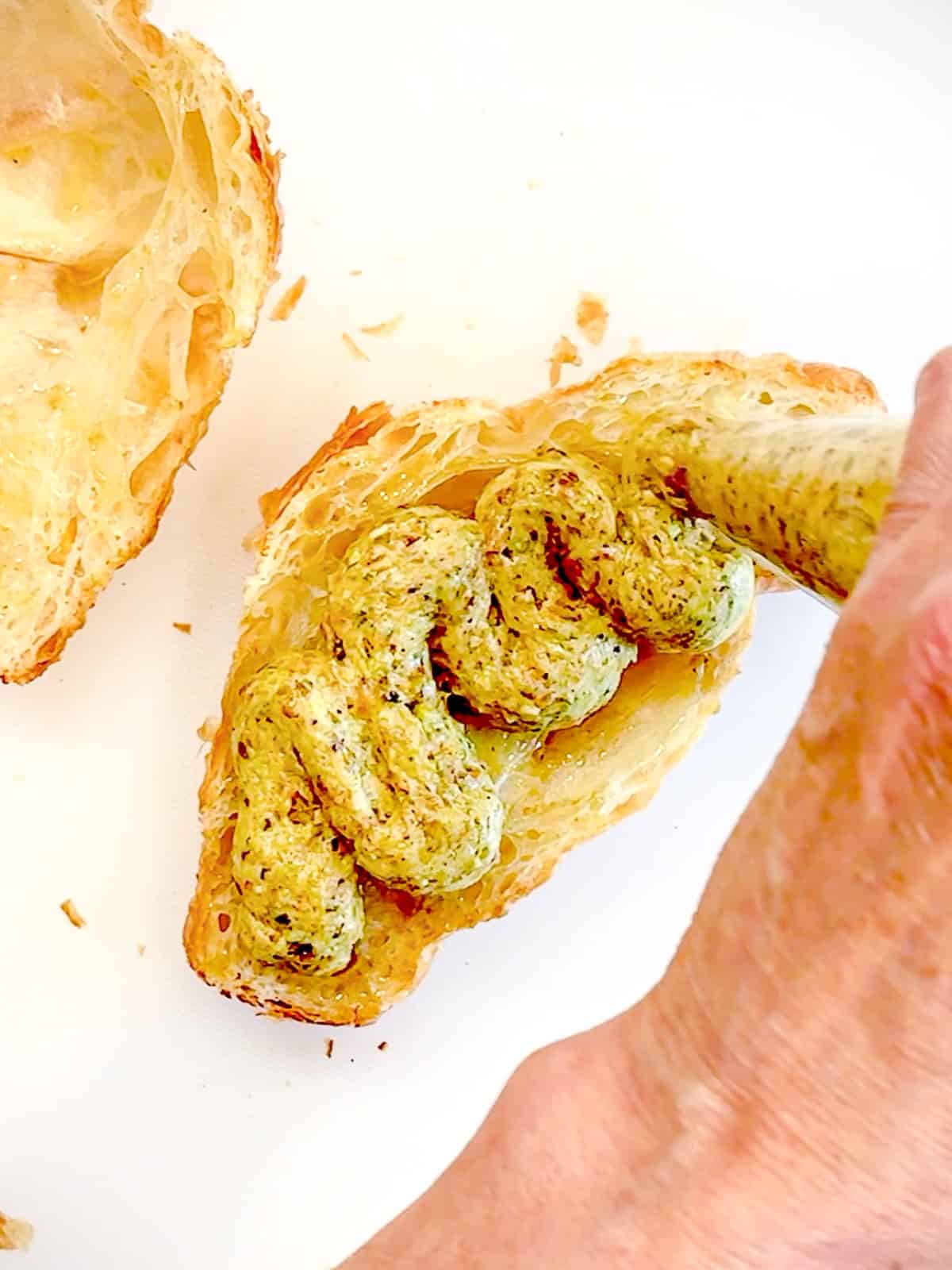 Piping pistachio cream inside of a sliced croissant.