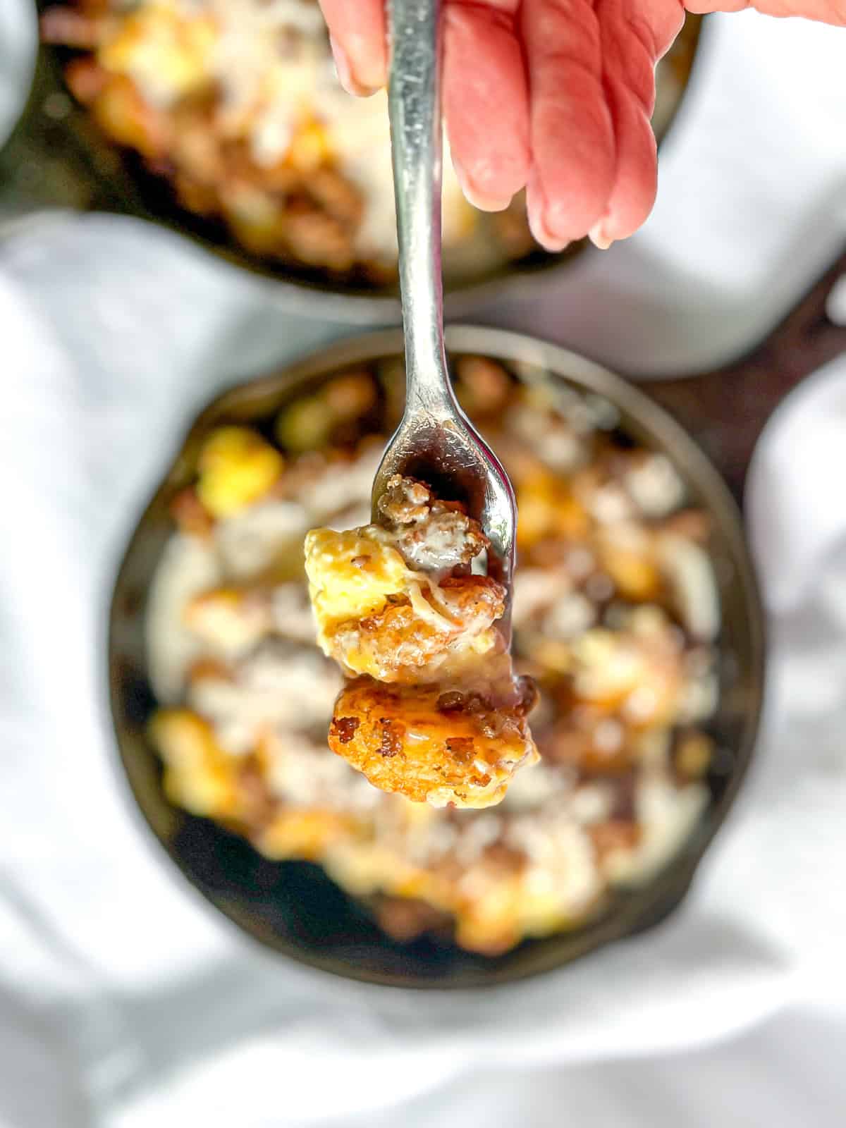 Forkful of tater tot breakfast skillet with sausage.